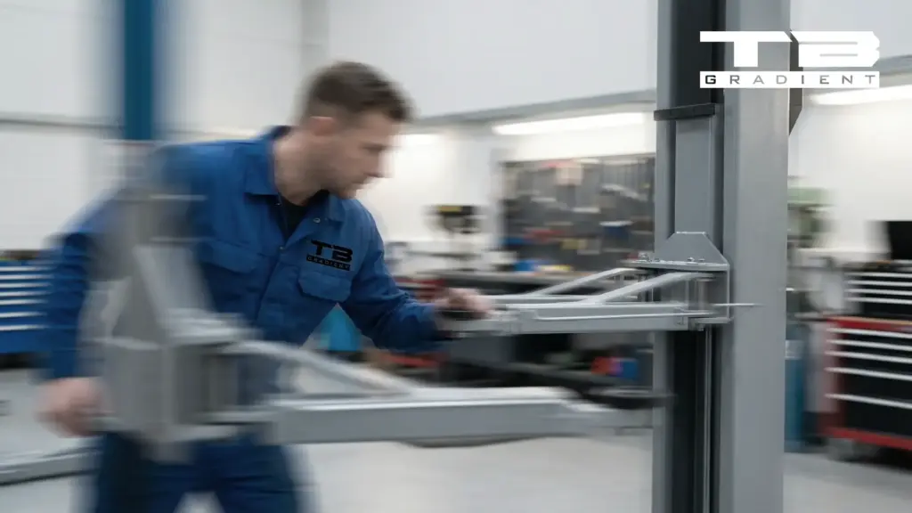 Techniker bedient einen Auslegerarm einer Hebesäule in einer Werkhalle, Bewegung unscharf dargestellt.